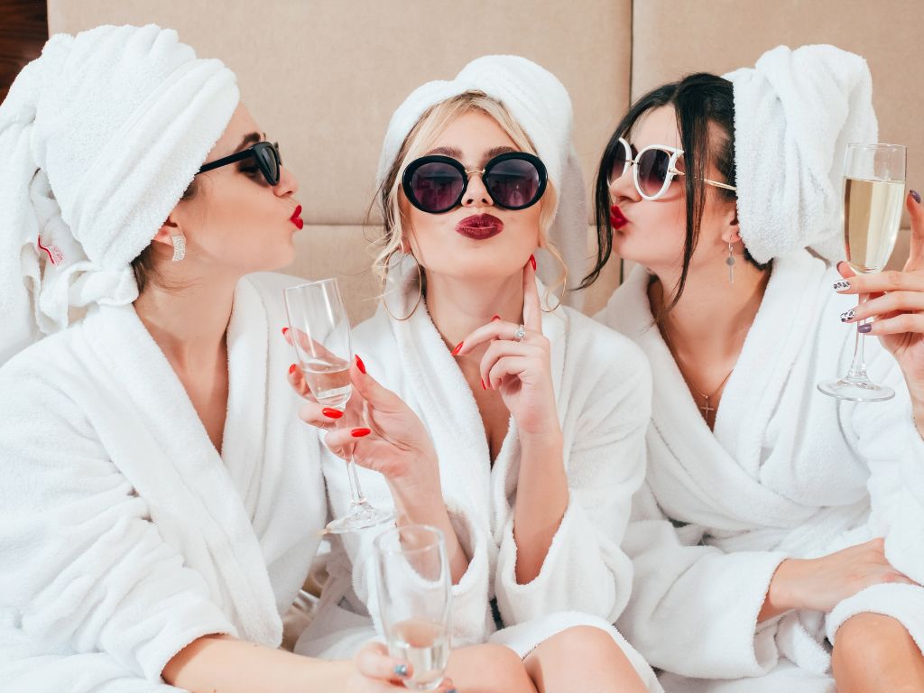 Three women in spa towels and sunglasses drinking Cremant de Bourogne sparkling wine
