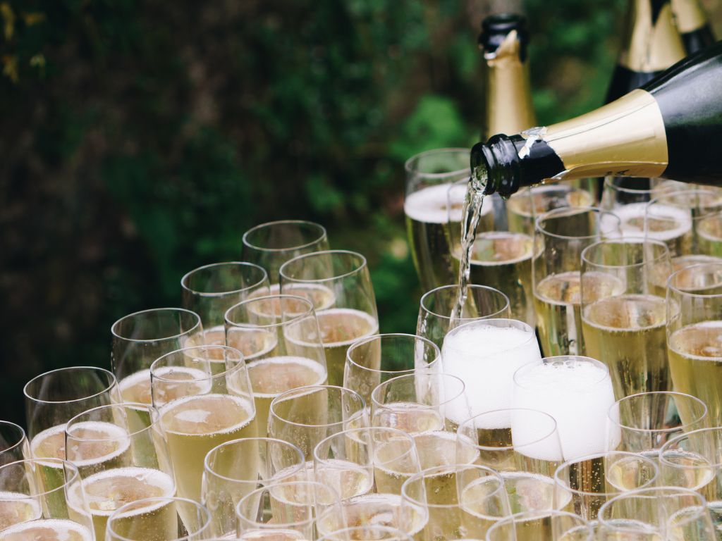 Cremant de Bourgogne being poured into a dozen champagne flutes