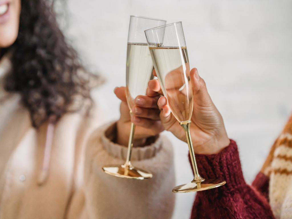 two peoples cheersing with sparkling wine in champagne flutes