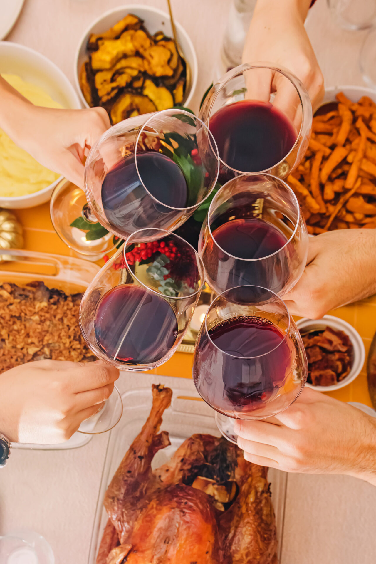 Five hands cheersing with red wine with turkey