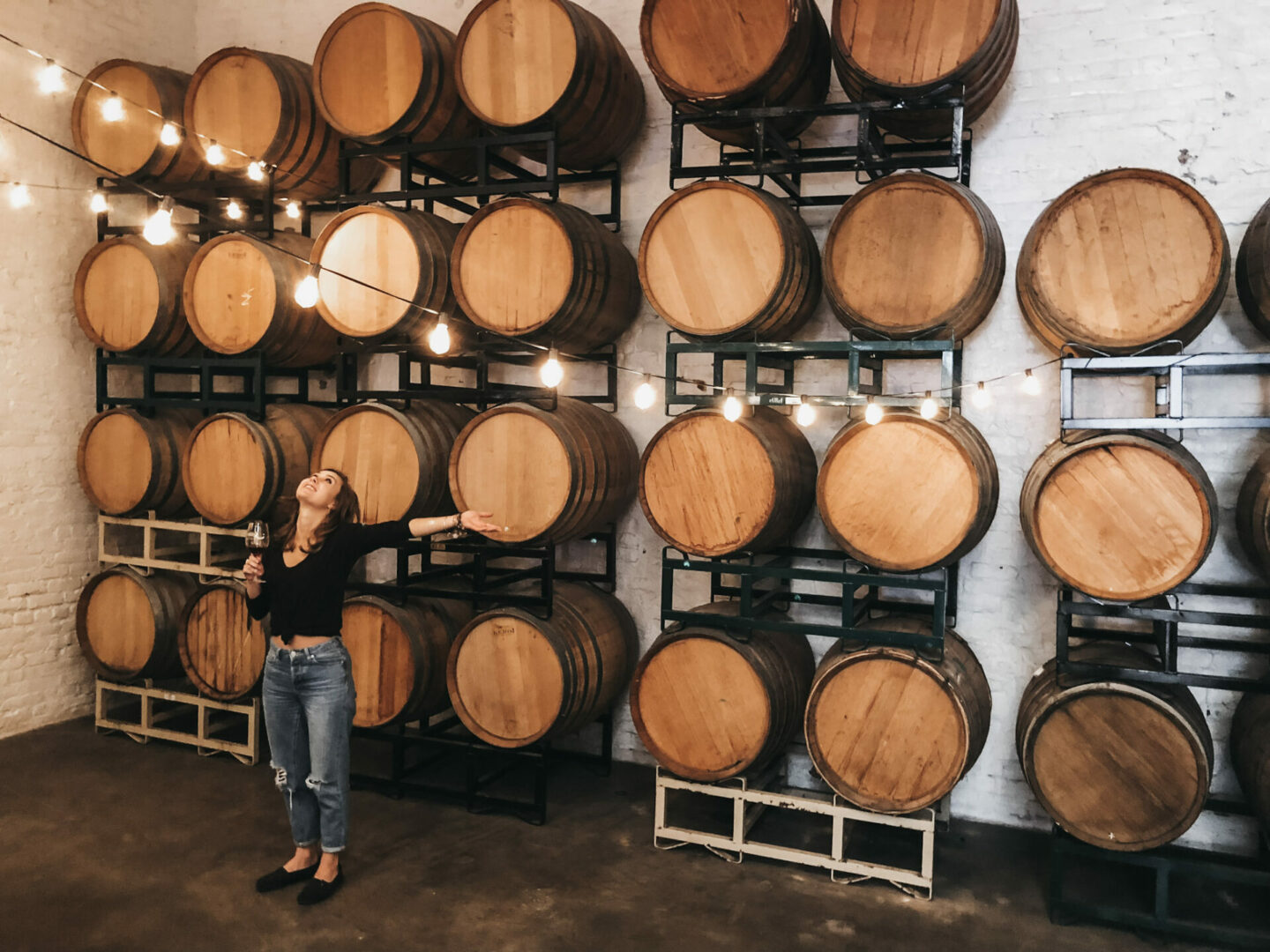 Paige in front of wine barrels in a winery