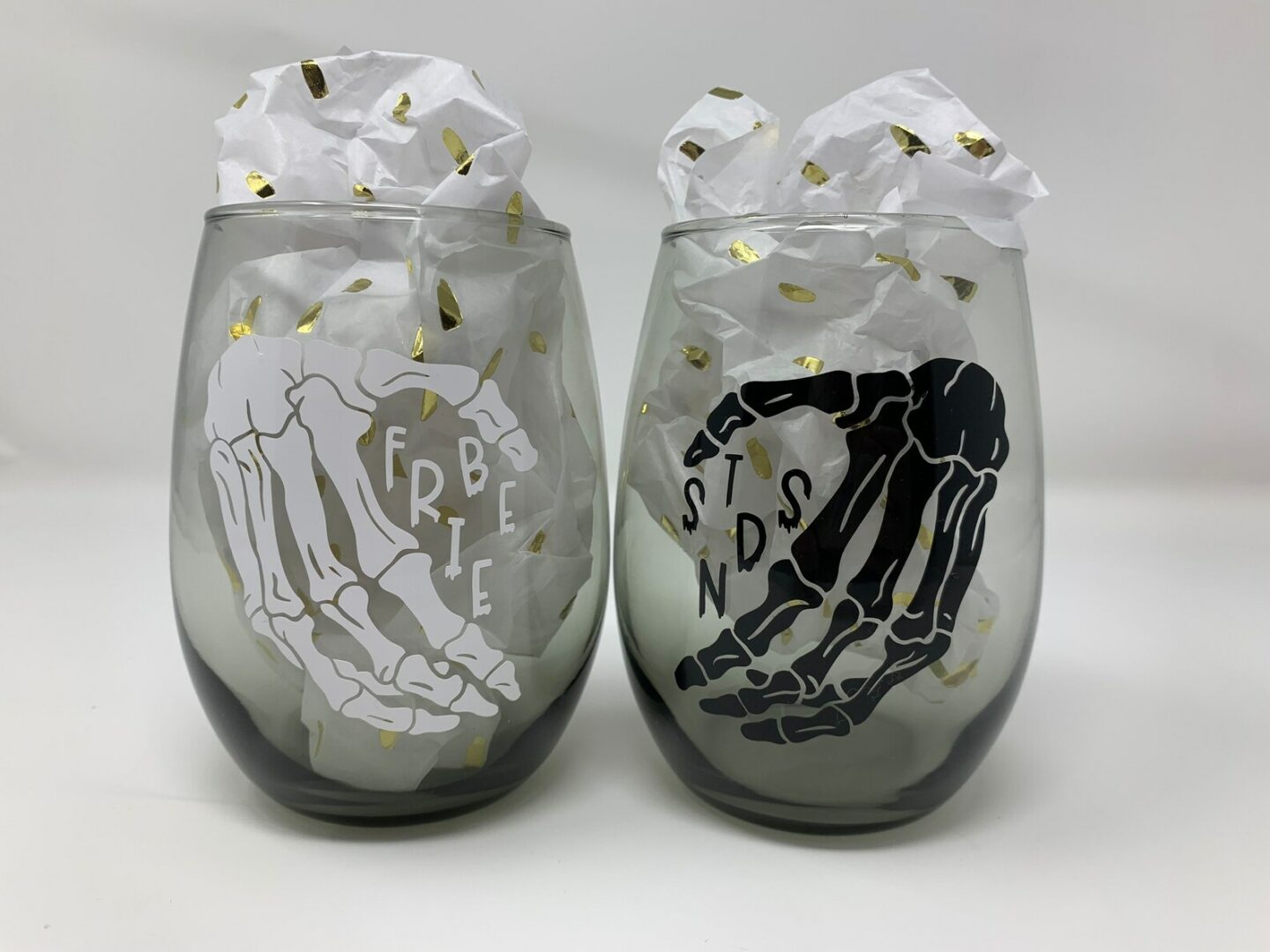 Two best friend skeleton hands cheers-ing two stemless wine glasses