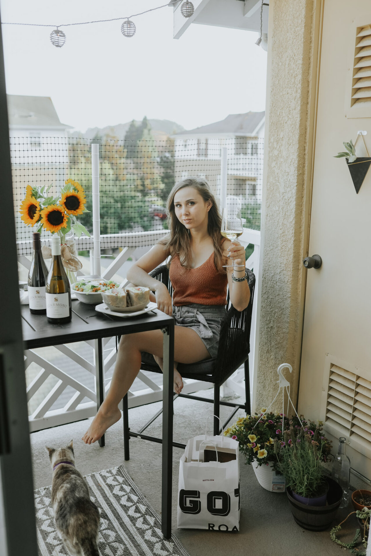 Should Chardonnay be chilled? Paige drinking chilled Chardonnay on patio with food pairing and sunflowers on table