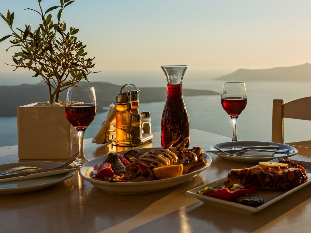 Two glasses of Merlot on a table with food pairings and a beautiful ocean view