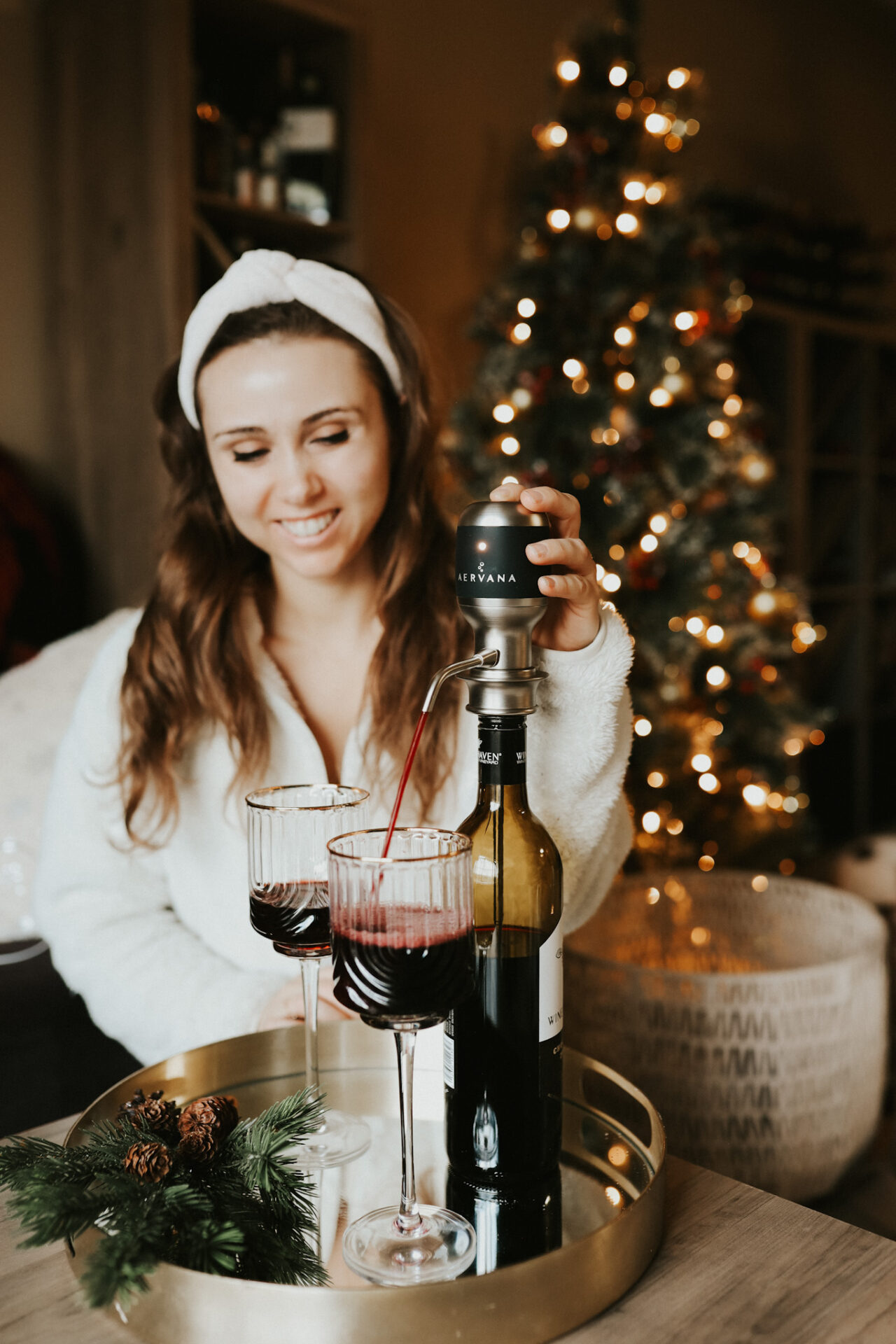 Aervana wine aerator on a table with Paige pressing the button to pour into a wine glass