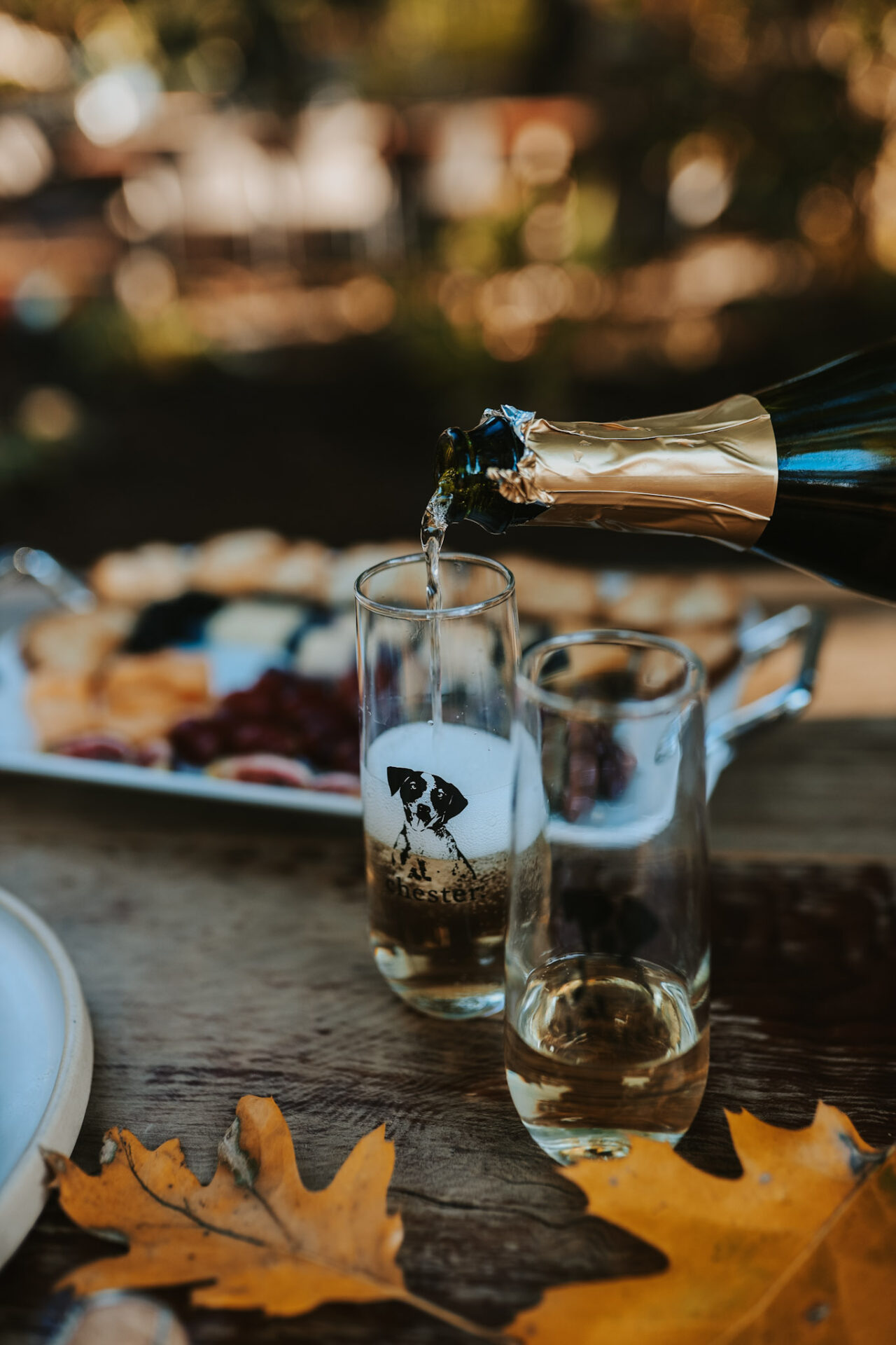 Champagne being poured into flutes with autumn leaves