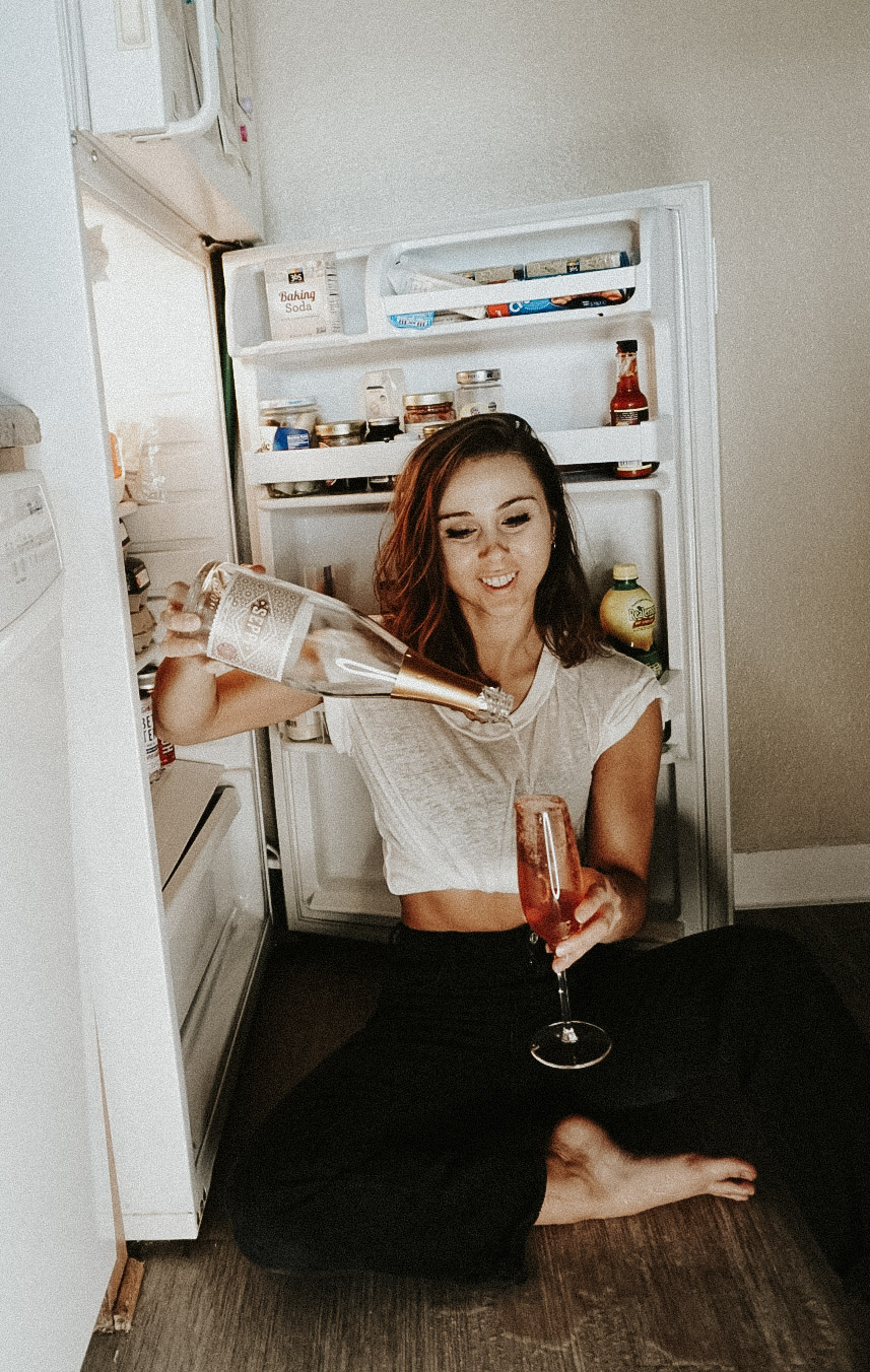 Paige pouring wine next to an open fridge. Does Champagne go bad?