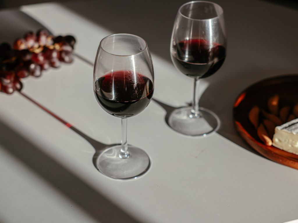 Two glasses of Pinot Noir on a table with grapes