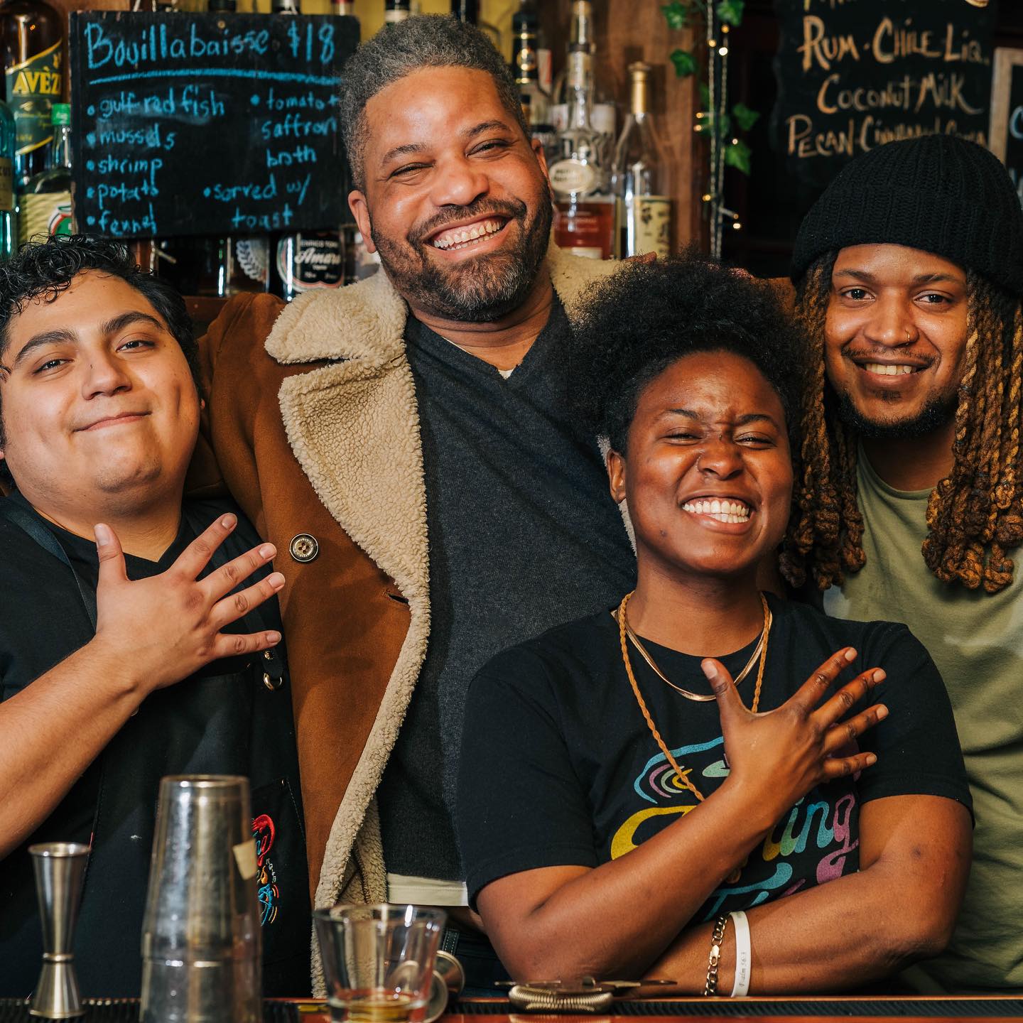 Staff members at Bacchanal Wine pose for a photo behind the bar