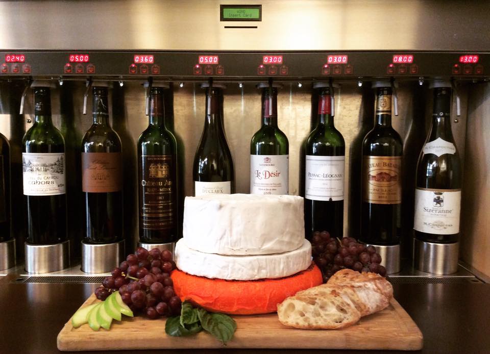 Cheeses and grapes artfully displayed in front of wines on tap