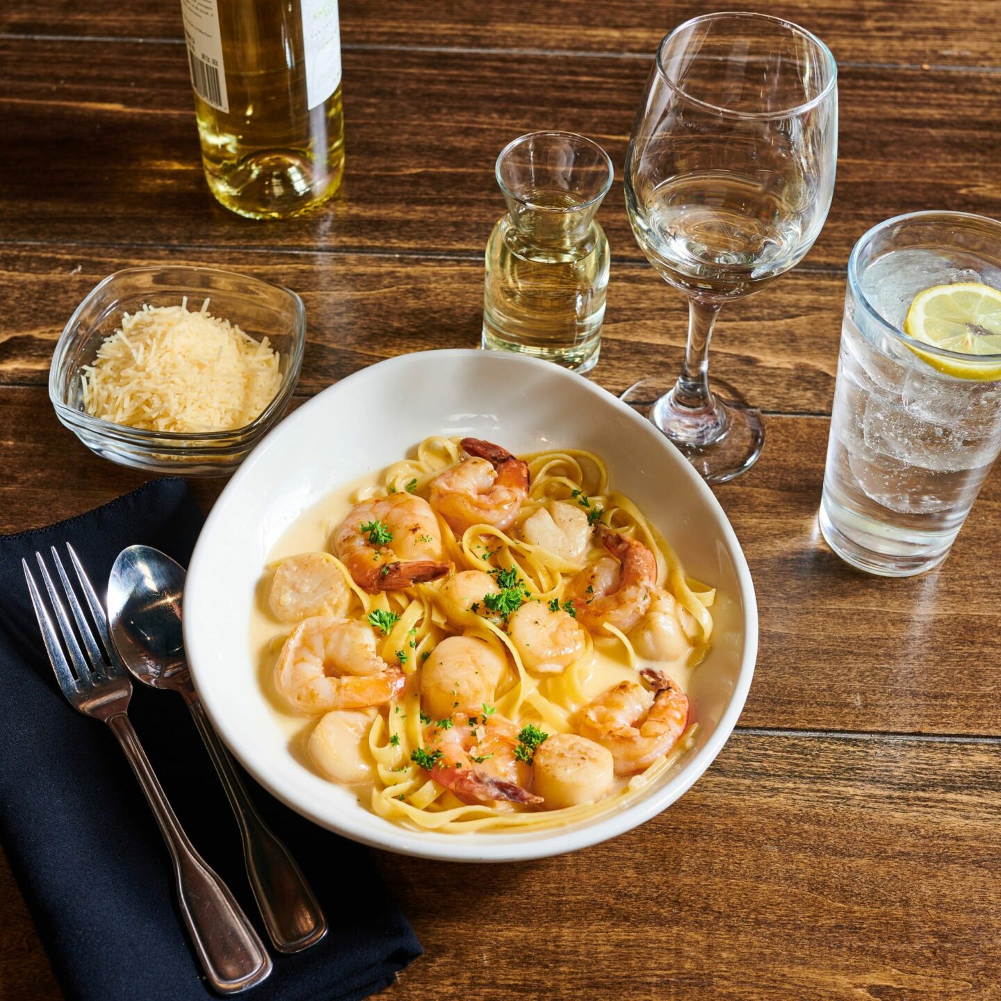 Seafood Fettuccine from Strizzi's photographed alongside a glass of white wine