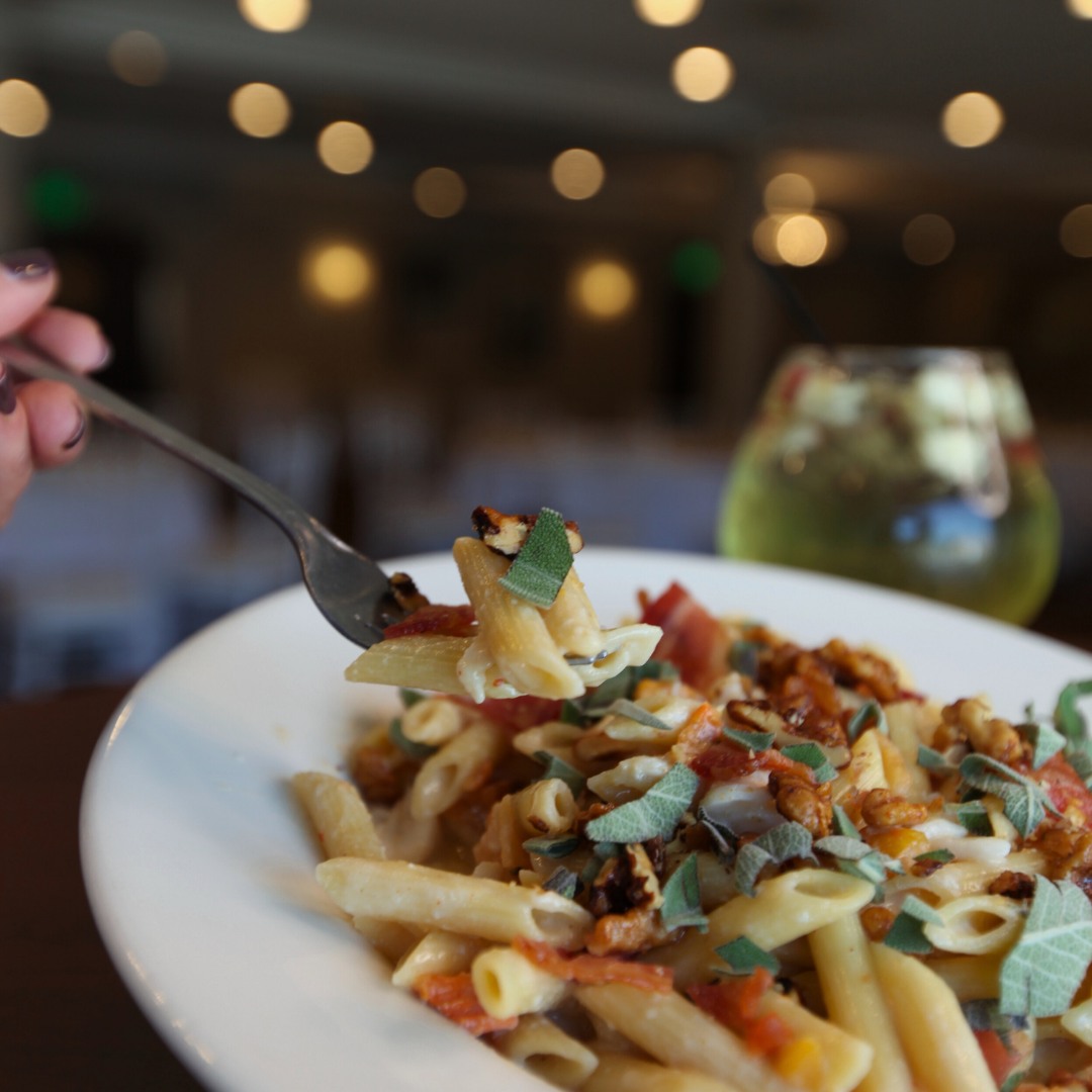 Hand holding a fork of pasta