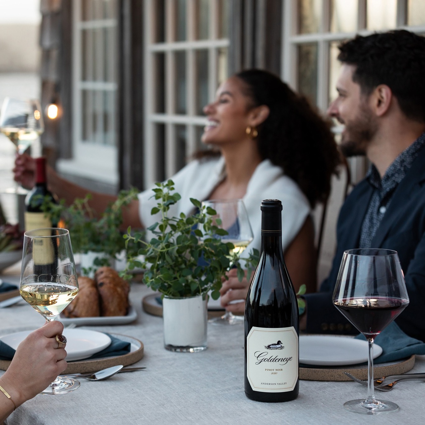 People sitting around a table eating and drinking wine