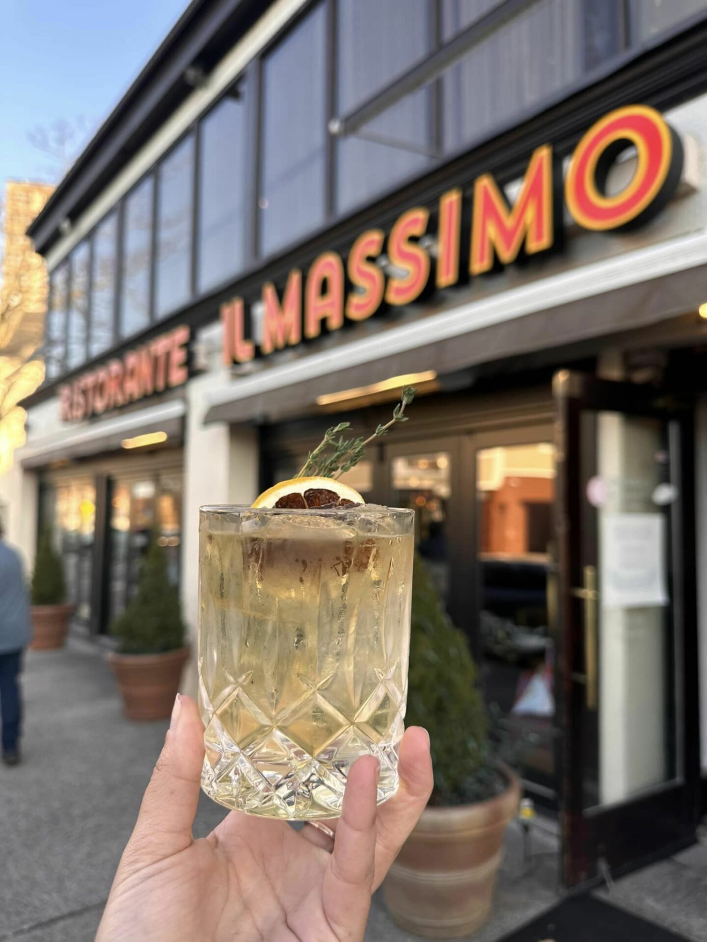 Hand holding a drink outside a restaurant sign