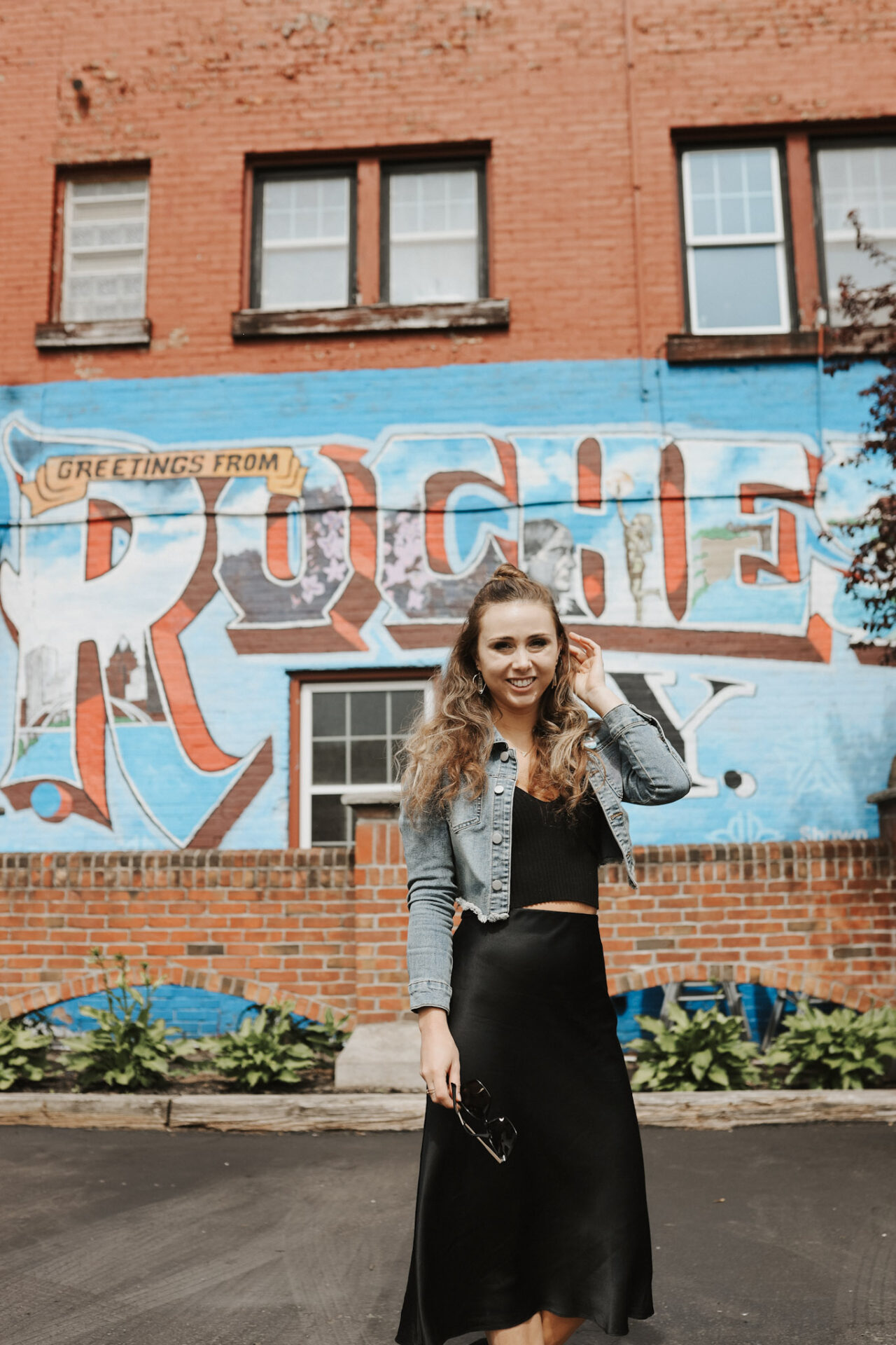 Paige in front of a Visit Rochester, NY mural