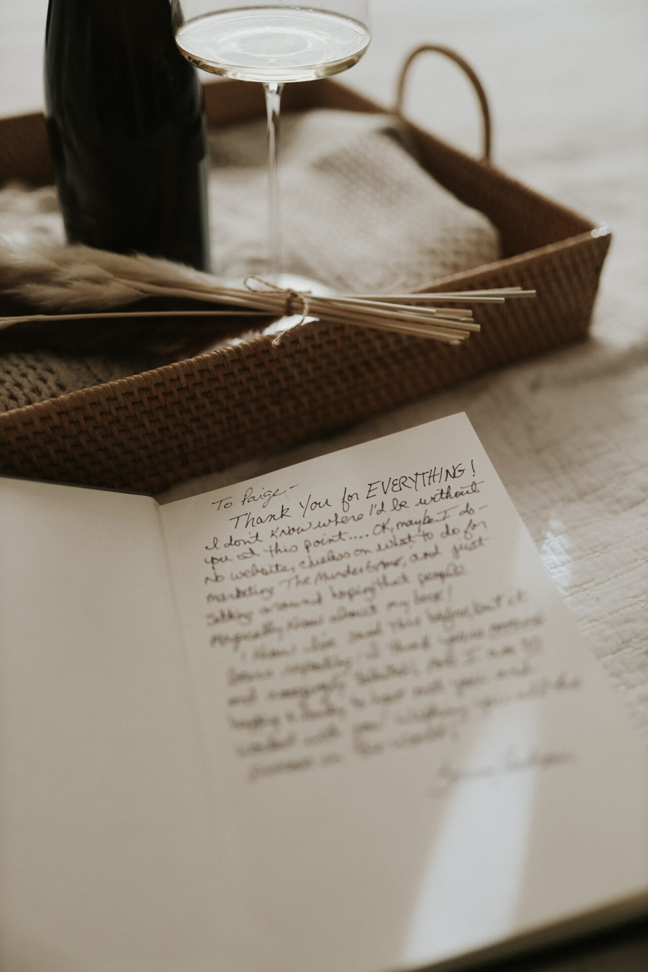 A handwritten thank-you note alongside a glass of wine